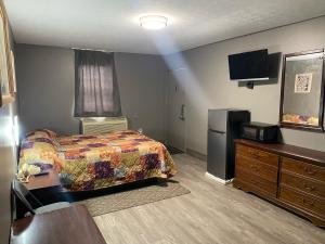 a bedroom with a bed and a refrigerator and a tv at Hoosier Travel Lodge in Jeffersonville