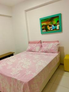 um quarto com uma cama rosa e uma pintura na parede em Apto moderno e bem localizado no Recife