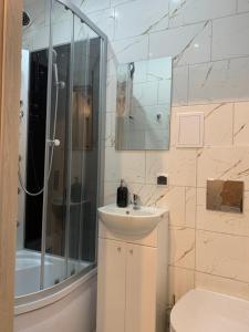 ein weißes Bad mit einem Waschbecken und einer Dusche in der Unterkunft Ropienka ski micro in Wańkowa