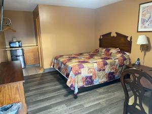 a hotel room with a bed and a table at Hoosier Travel Lodge in Jeffersonville