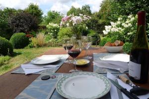 uma mesa com pratos e taças de vinho em La ferme aux oiseaux B&B em Beaumont