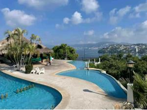 a swimming pool at a resort with a view of the ocean at LOFT. 208 in Acapulco
