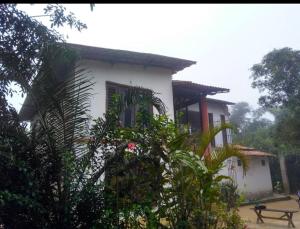 Pousada Raízes Guaramiranga في غواراميرانغا: بيت ابيض ومقعد امامه