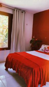1 dormitorio con cama roja y ventana en Pousada Raízes Guaramiranga, en Guaramiranga
