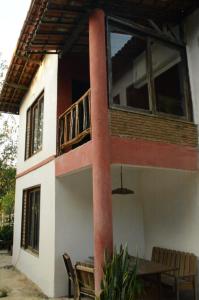 een huis met een balkon en een tafel en stoelen bij Pousada Raízes Guaramiranga in Guaramiranga
