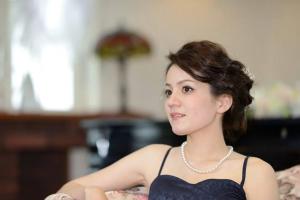 a woman in a black dress sitting on a bed at Agri In Holiday in Hirosaki