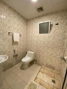 a bathroom with a toilet and a tv on the wall at ذوق الخيال للشقق المخدومة Dhoq Alkhayal in Al Ahsa