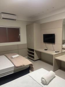 a bedroom with a bed and a desk with a television at Mustang Hotel in Salgueiro