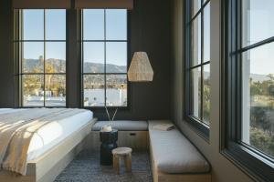Dormitorio con ventanas, cama y banco en Drift Santa Barbara en Santa Bárbara