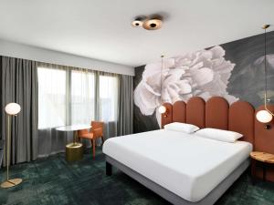 a bedroom with a large bed with a flower painting on the wall at Mercure Debrecen in Debrecen