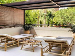 eine Terrasse mit Bänken und Tischen auf dem Balkon in der Unterkunft Mercure Benidorm in Benidorm