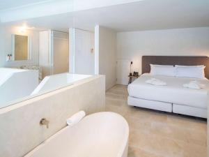 a white bathroom with a tub and a bed and a bath tub at Mercure Benidorm in Benidorm