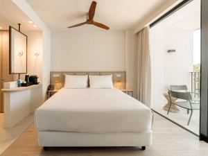 a bedroom with a white bed and a balcony at Mercure Benidorm in Benidorm