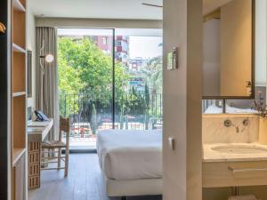 a bedroom with a bed and a bathroom with a sink at Mercure Benidorm in Benidorm