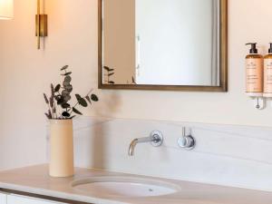 a bathroom sink with a mirror and a vase with a plant at Mercure Benidorm in Benidorm