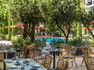 an outdoor dining area with tables and chairs and a pool at Mercure Benidorm in Benidorm