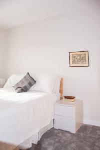 Cama blanca con almohada y mesita de noche en 2 bed 2 bath Apartment with Canal View, en Dublín