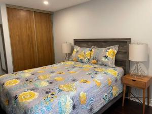 ein Schlafzimmer mit einem Bett mit einer bunten Bettdecke und zwei Lampen in der Unterkunft Modern main floor 3-bedroom apartment backing onto a park in Mississauga
