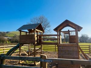a wooden playground with a slide in a fence at Heron in Nantmel +7 photos