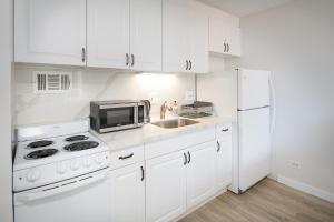 Biała kuchnia ze zlewem i kuchenką mikrofalową w obiekcie PRIME Location - Waikiki Full Kitchen& Laundry w mieście Honolulu