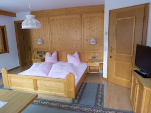 a bedroom with a bed with white sheets and pink pillows at Haus Dorfplatz in Galtür