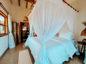 1 dormitorio con 1 cama con mosquitera blanca en Heruê Vila Praia do Espelho, en Porto Seguro