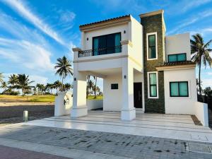 Cette maison blanche dispose d'un balcon et de palmiers. dans l'établissement Estrella del mar · Hermosa casa vacacional, à Barrón