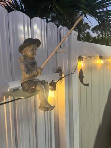 Uma estátua de um rapaz sentado num poste numa cerca. em Villa San Carlos Park em Fort Myers