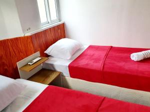 Matianellu Hostel في ريو دي جانيرو: غرفة نوم بسريرين بملاءات حمراء وبيضاء