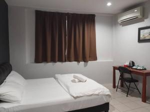 um quarto com uma cama, uma secretária e uma janela em Reintree Lodge Hotel em Ipoh