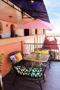 uma mesa e cadeiras numa varanda com um guarda-sol rosa em Hotel Los Balcones Leon em León
