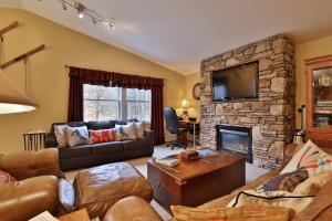 una sala de estar con sofás y una chimenea de piedra. en The Tanglewood Lodge- Amazing Ski Home for Groups, Hot Tub, Close to Killington Resort! home, en Killington