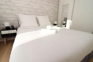 a white bed in a bedroom with a brick wall at Votre confort la Cosy Cocoon in Courcouronnes