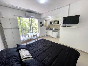 1 dormitorio con 1 cama negra grande y cocina en Agradable monoambiente en Urquiza- Incas1 en Buenos Aires