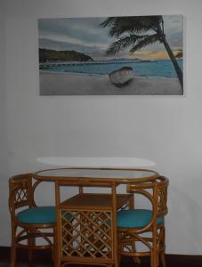 een tafel en twee stoelen met een foto aan de muur bij Oskar's Rain Forest Retreat in Nelly Bay