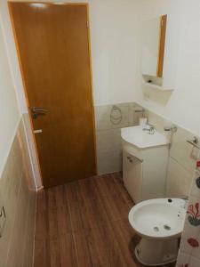 een badkamer met een toilet, een wastafel en een deur bij Dpto Senderos de Andorra - USHUAIA in Ushuaia