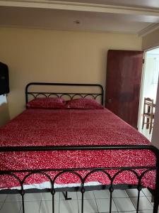 a bed in a bedroom with a red comforter at TETE Comforts in Roseau