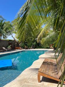 a swimming pool with a bench next to a palm tree at Casa grande 12 pessoas Rio das onças in Fortim