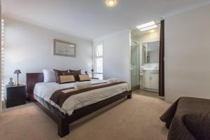 a bedroom with a large bed and a bathroom at Beach View Apartment in Cottesloe in Perth