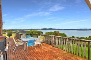 a table and chairs on a deck with a view of the water at Kiama Sunset On George's in St Helens