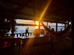 a person sitting in a hammock at a restaurant with the sunset at Maloca Barü in Macedonia