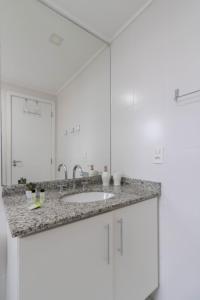 a white bathroom with a sink and a mirror at Family Apartment - GRU in Guarulhos