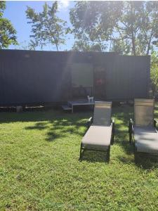 two chairs sitting in the grass in a field at Ojochal studio design conteneur & jardin in Ojochal