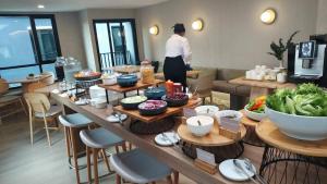 a woman standing in a room with a table of food at Wellness Stay & Hotel Sukhumvit 107 in Bangna