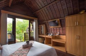 a bedroom with a bed and a desk and a television at Klumpu Hill Villas Nusa Penida in Klungkung