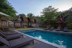 a swimming pool with chairs and a house at Klumpu Hill Villas Nusa Penida in Klungkung