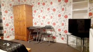 a room with a table and two chairs and a television at Penzance Cottage in Penzance