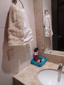 a bathroom with a sink and a mirror and towels at Lindo Flat em resort silencioso e aconchegante in Brasilia