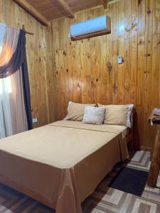 Cama en habitación con pared de madera en Los Pioneros en Puerto Iguazú