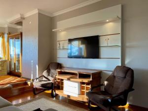 sala de estar con 2 sillas y TV de pantalla plana en Bela Vista Gramado, en Gramado